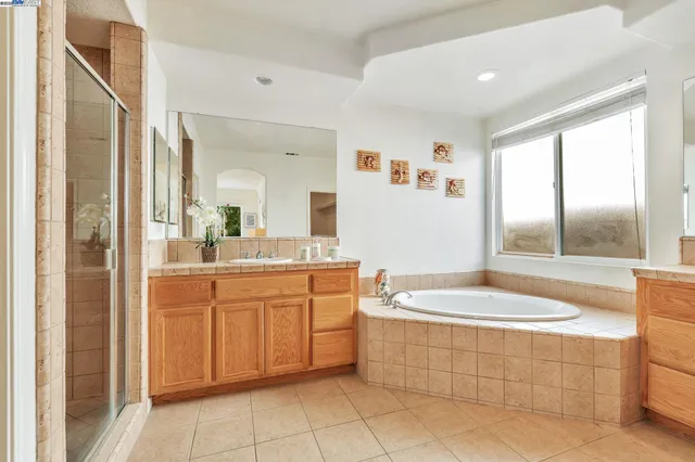 a spacious bathroom with a sink a mirror a bathtub and next to a window