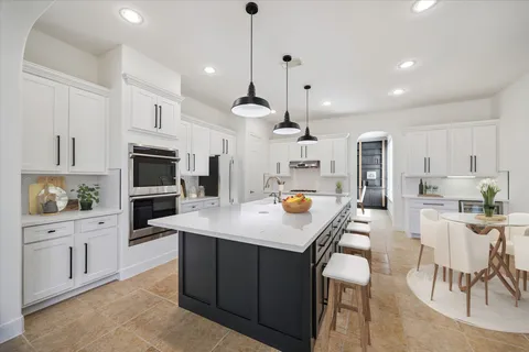 a kitchen with stainless steel appliances kitchen island granite countertop a stove a sink a oven a dining table and chairs with wooden floor