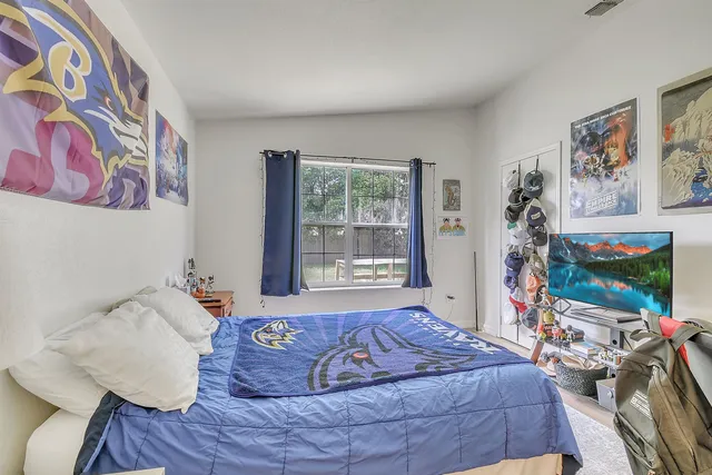 a bed sitting in a bedroom next to a window with a flat screen tv