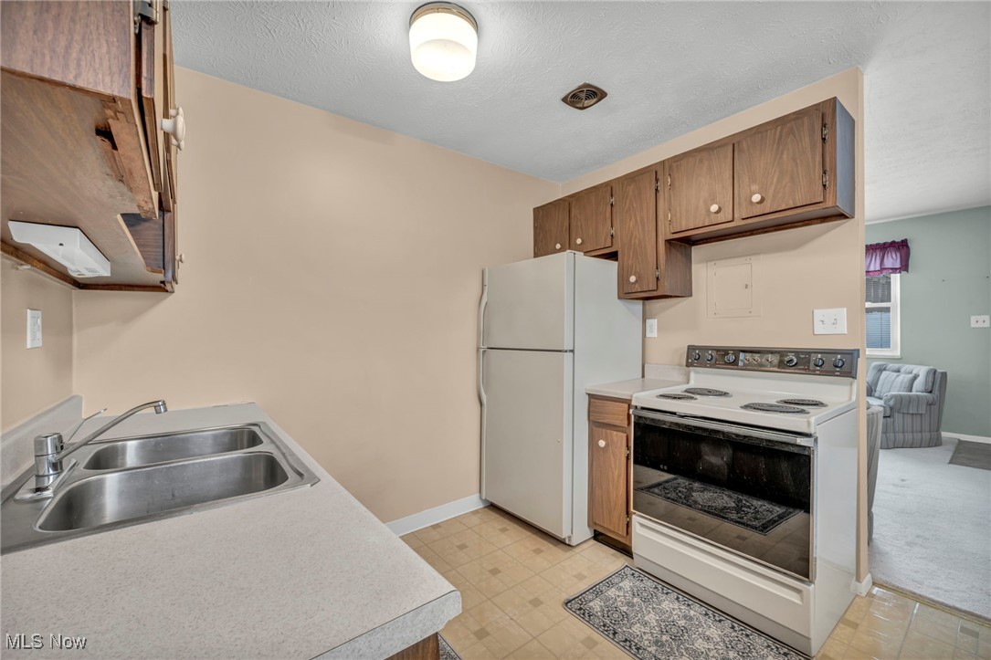 5651 Broadview Road, Unit C1 Cleveland, OH 44134 - Photo 8 of 23 Kitchen with white appliances, light floors, light countertops, a textured ceiling, and brown cabinetry