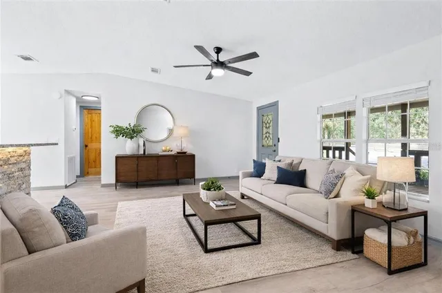 a view of a kitchen with wooden floor a ceiling fan and windows