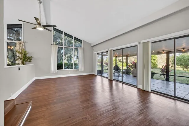 a view of empty room with wooden floor and fan