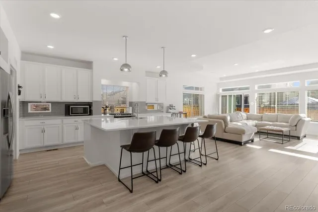 a kitchen with stainless steel appliances granite countertop a sink a stove a refrigerator and white cabinets with wooden floor