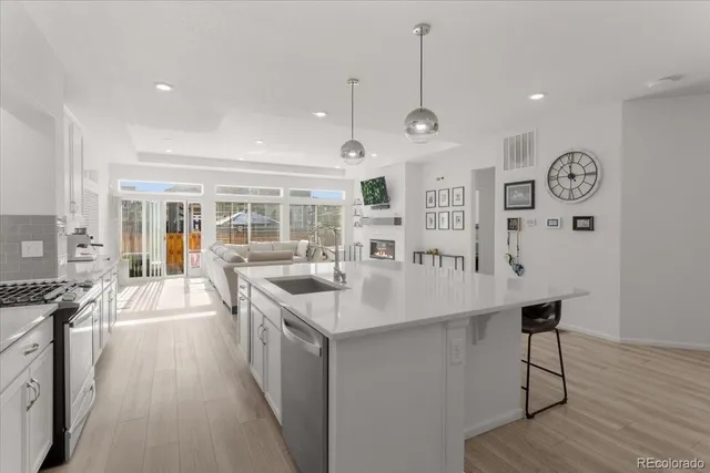 a large kitchen with stainless steel appliances a large counter space a stove and a wooden floors