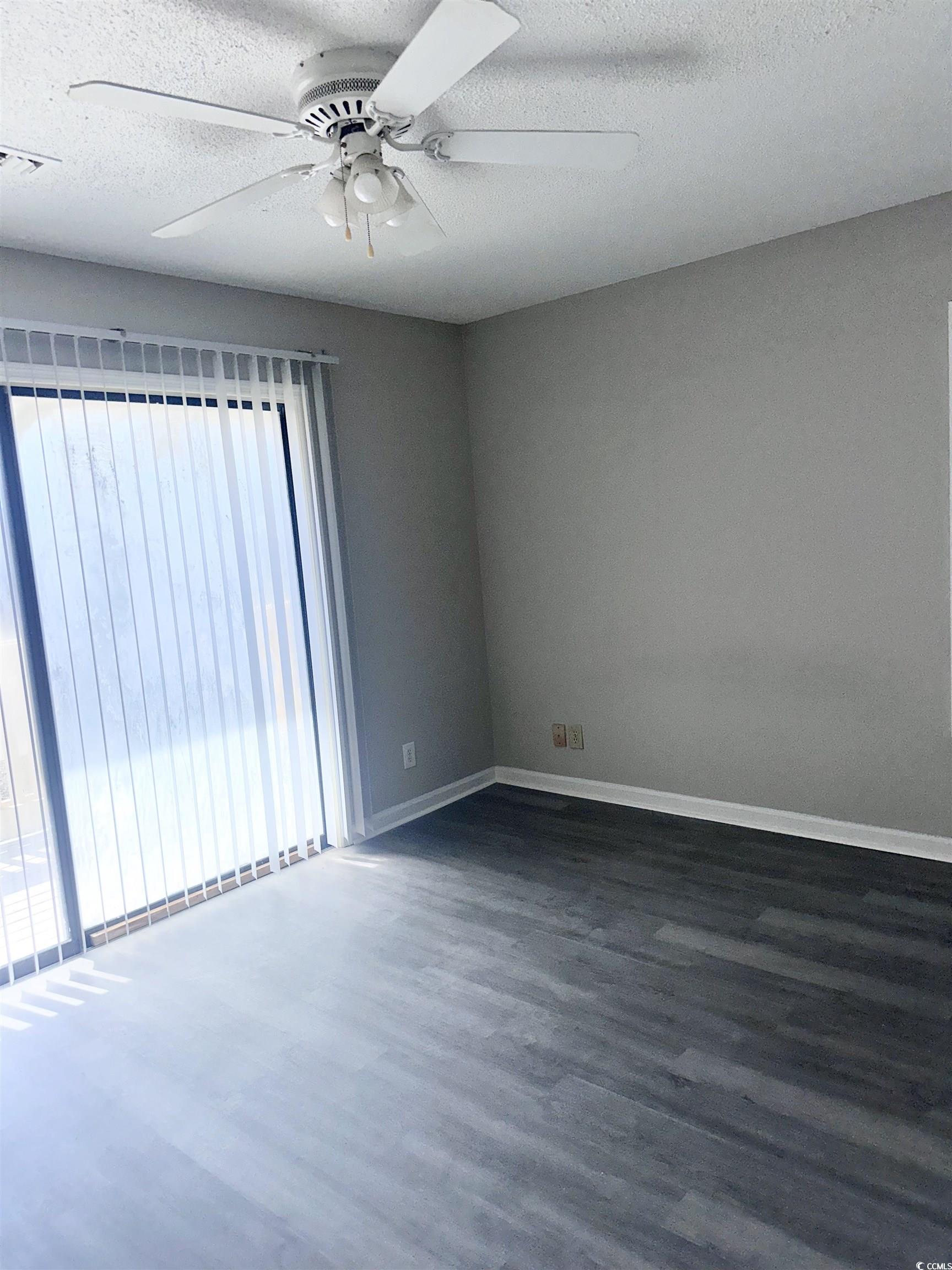 401 Garden Drive, Unit 100B Myrtle Beach, SC 29575 - Photo 13 of 23 Empty room featuring wood finished floors, ceiling fan, and a textured ceiling