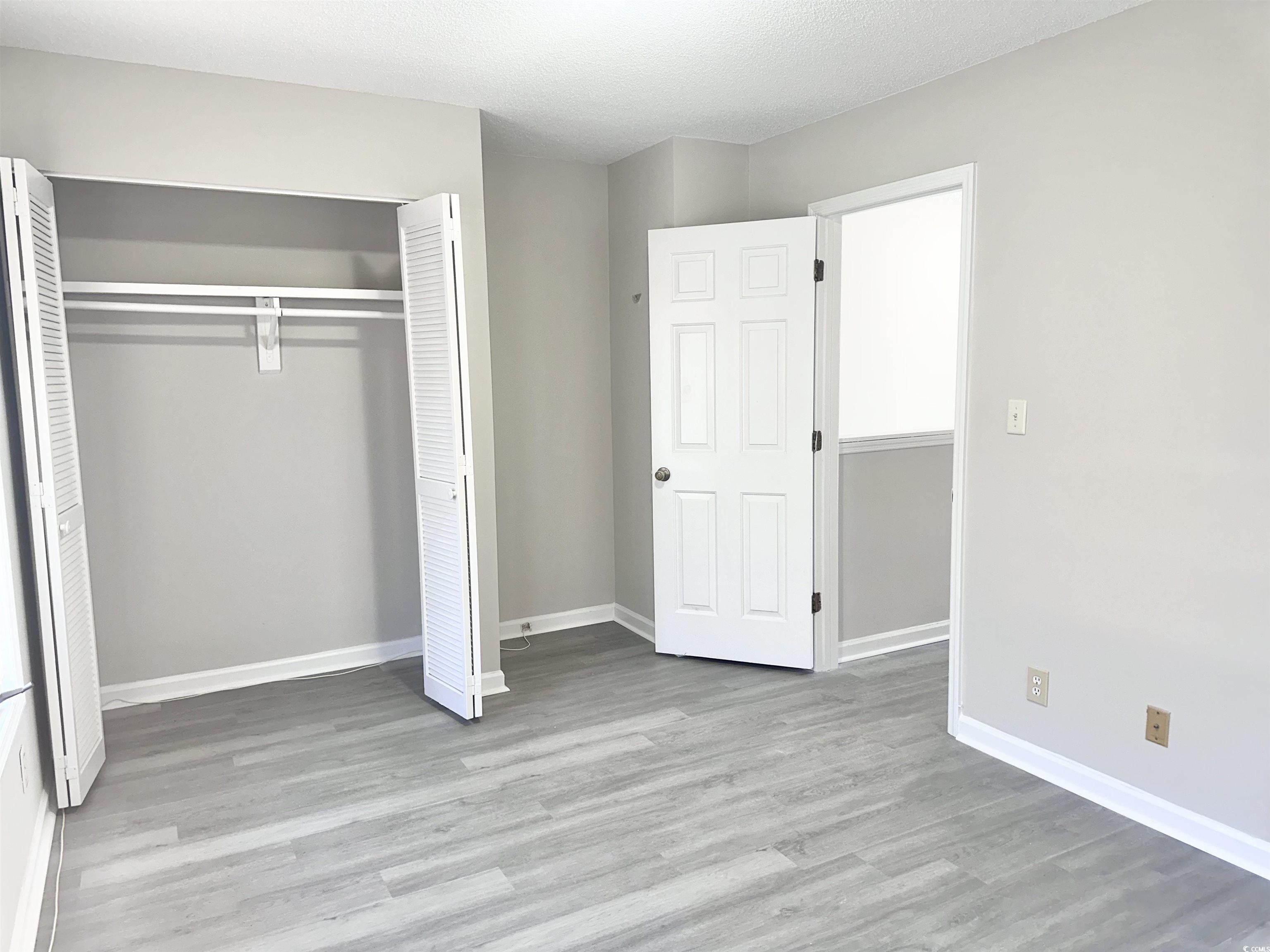 401 Garden Drive, Unit 100B Myrtle Beach, SC 29575 - Photo 19 of 23 Unfurnished bedroom featuring a closet and wood finished floors