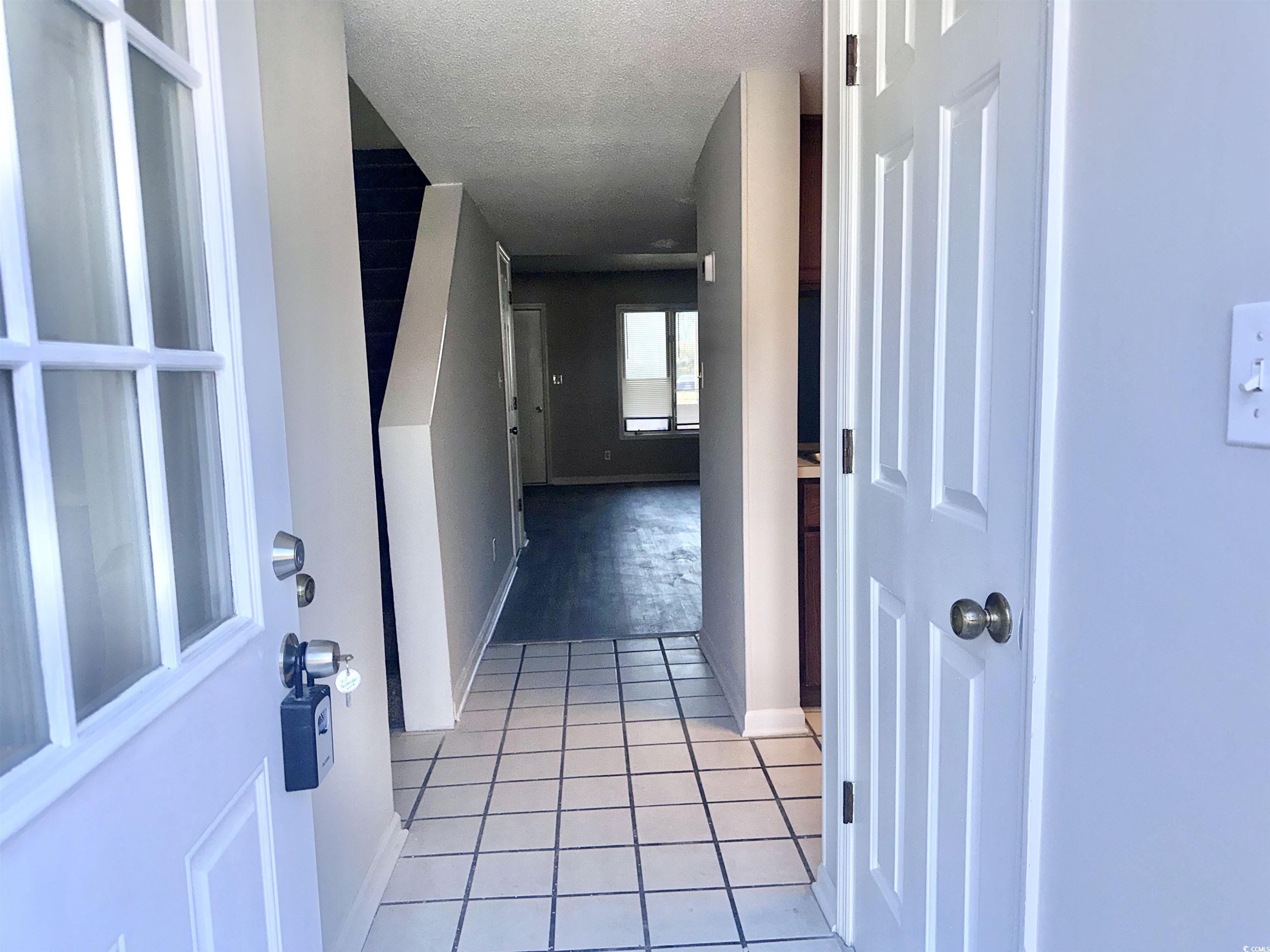 401 Garden Drive, Unit 100B Myrtle Beach, SC 29575 - Photo 3 of 23 Hallway with a textured ceiling and light tile patterned flooring