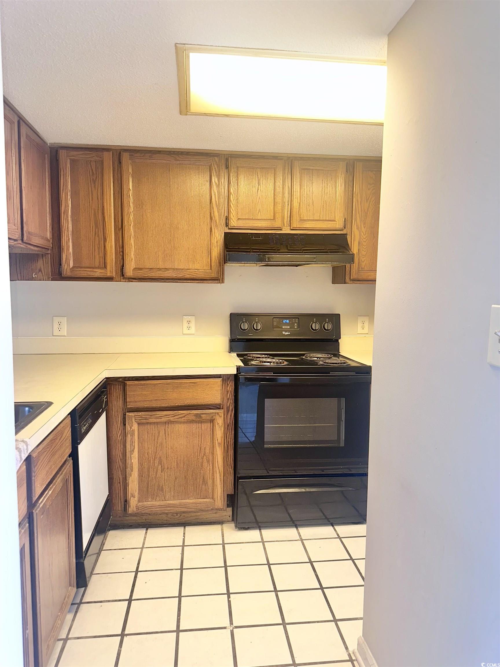 401 Garden Drive, Unit 100B Myrtle Beach, SC 29575 - Photo 5 of 23 Kitchen featuring black range with electric stovetop, white dishwasher, under cabinet range hood, light countertops, and light tile patterned flooring