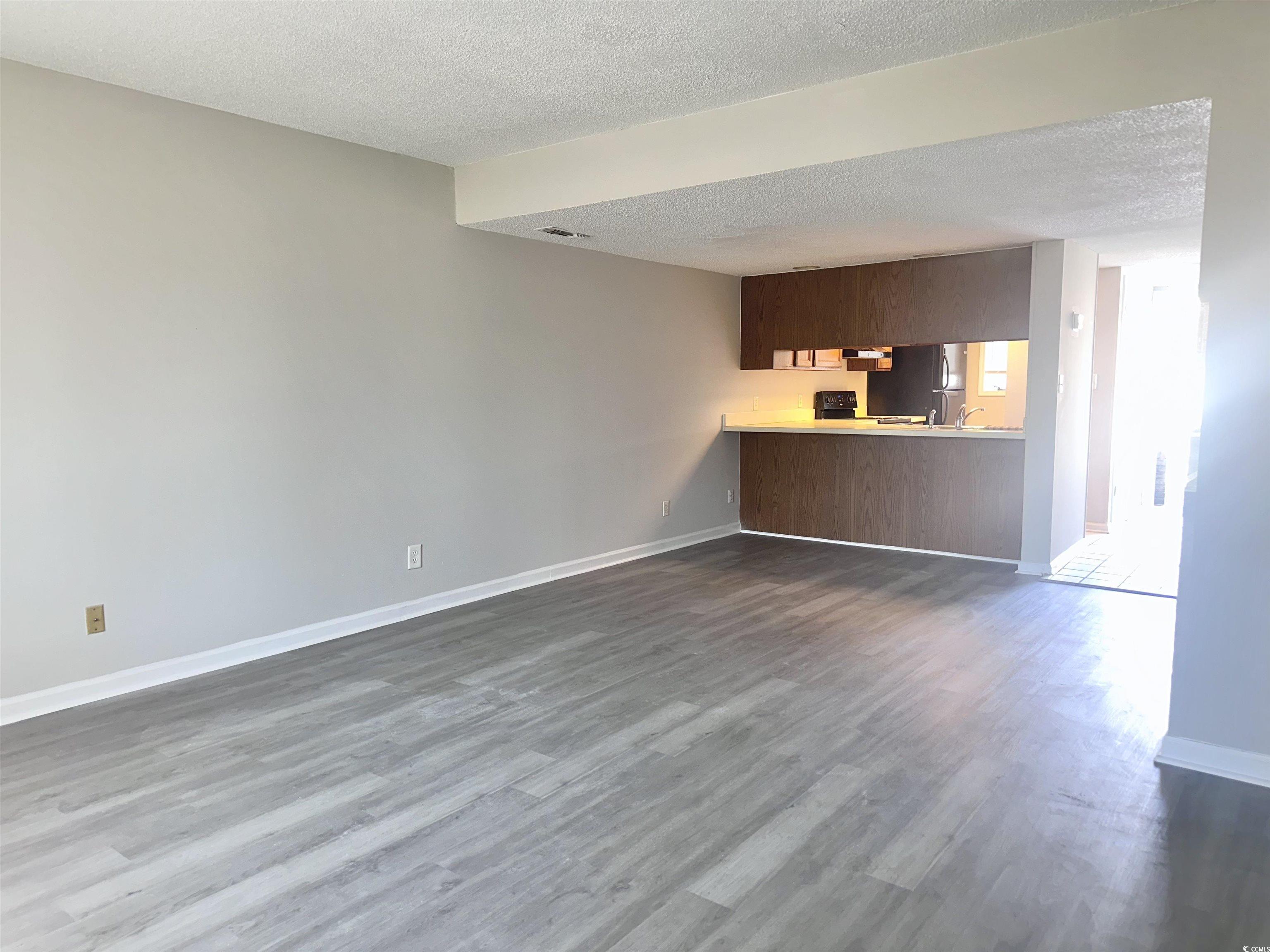 401 Garden Drive, Unit 100B Myrtle Beach, SC 29575 - Photo 7 of 23 Unfurnished living room with a textured ceiling and dark wood-type flooring