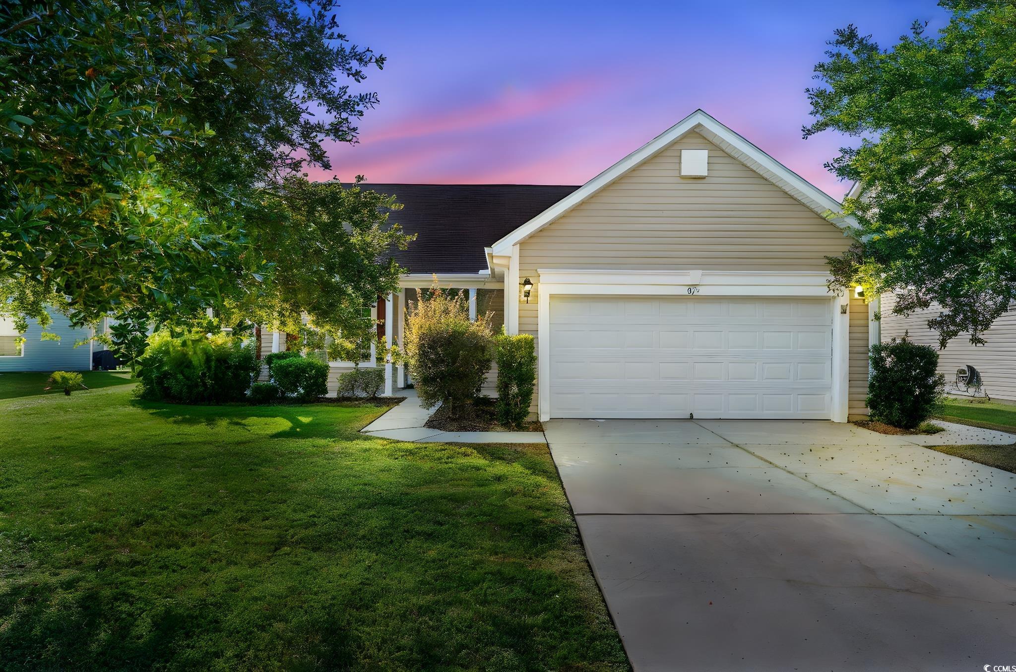 View of front facade featuring concrete driveway, a front lawn, and a garage