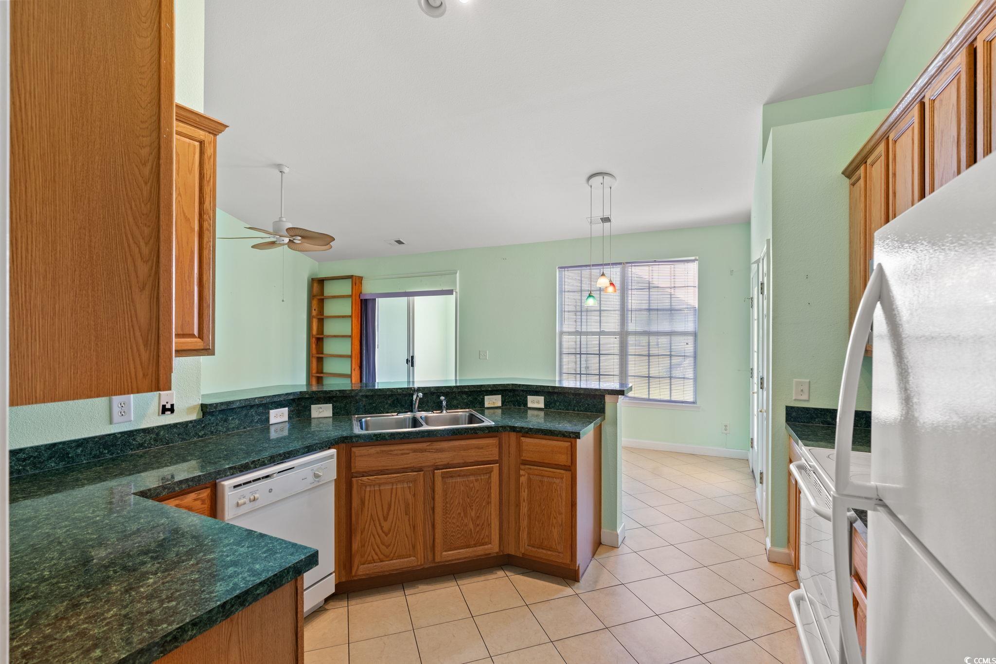 875 Brookline Drive Myrtle Beach, SC 29579 - Photo 12 of 40 Kitchen with white appliances, brown cabinetry, and dark countertops