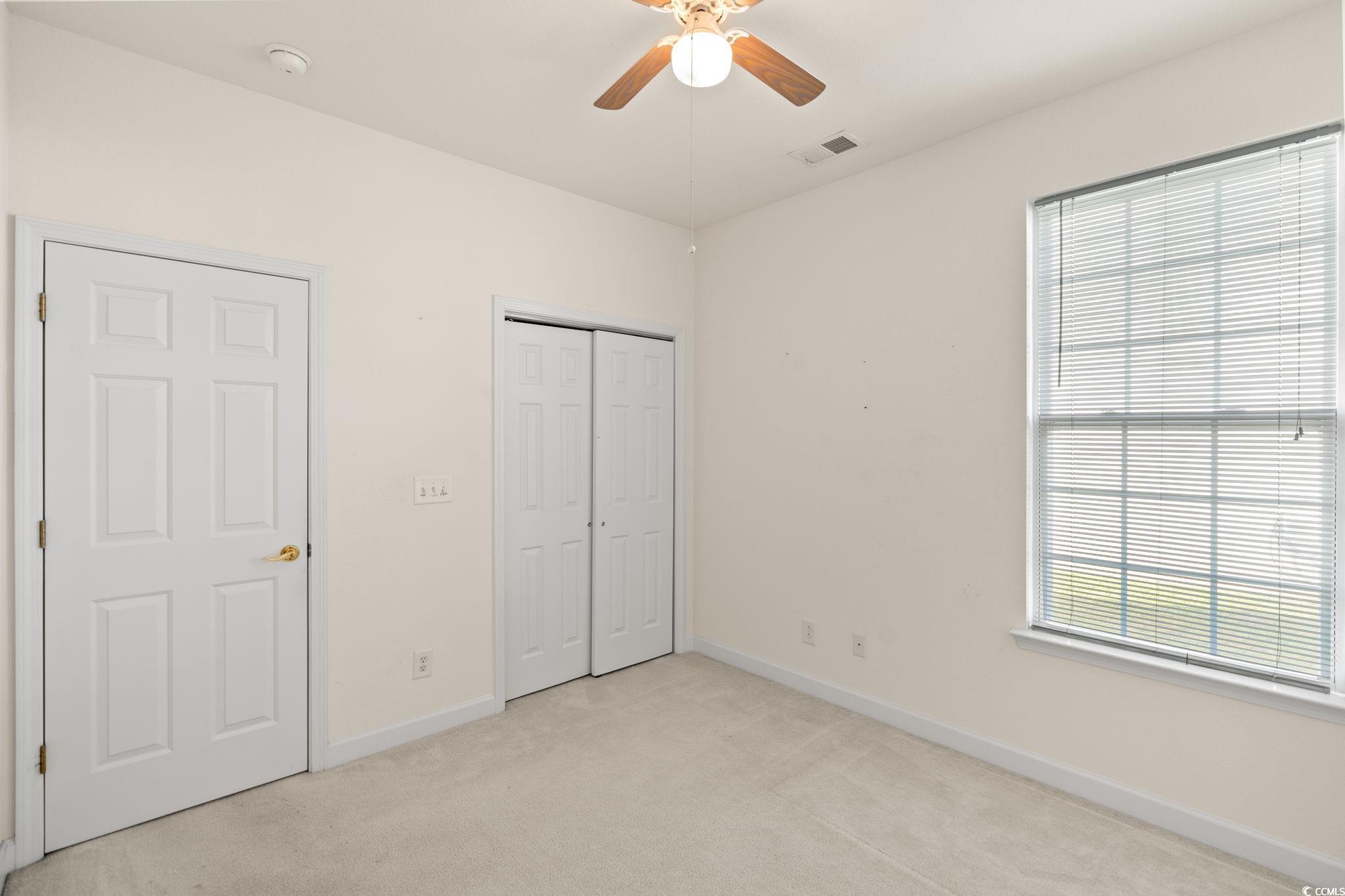 875 Brookline Drive Myrtle Beach, SC 29579 - Photo 24 of 40 Unfurnished bedroom with multiple windows, light carpet, ceiling fan, and a closet