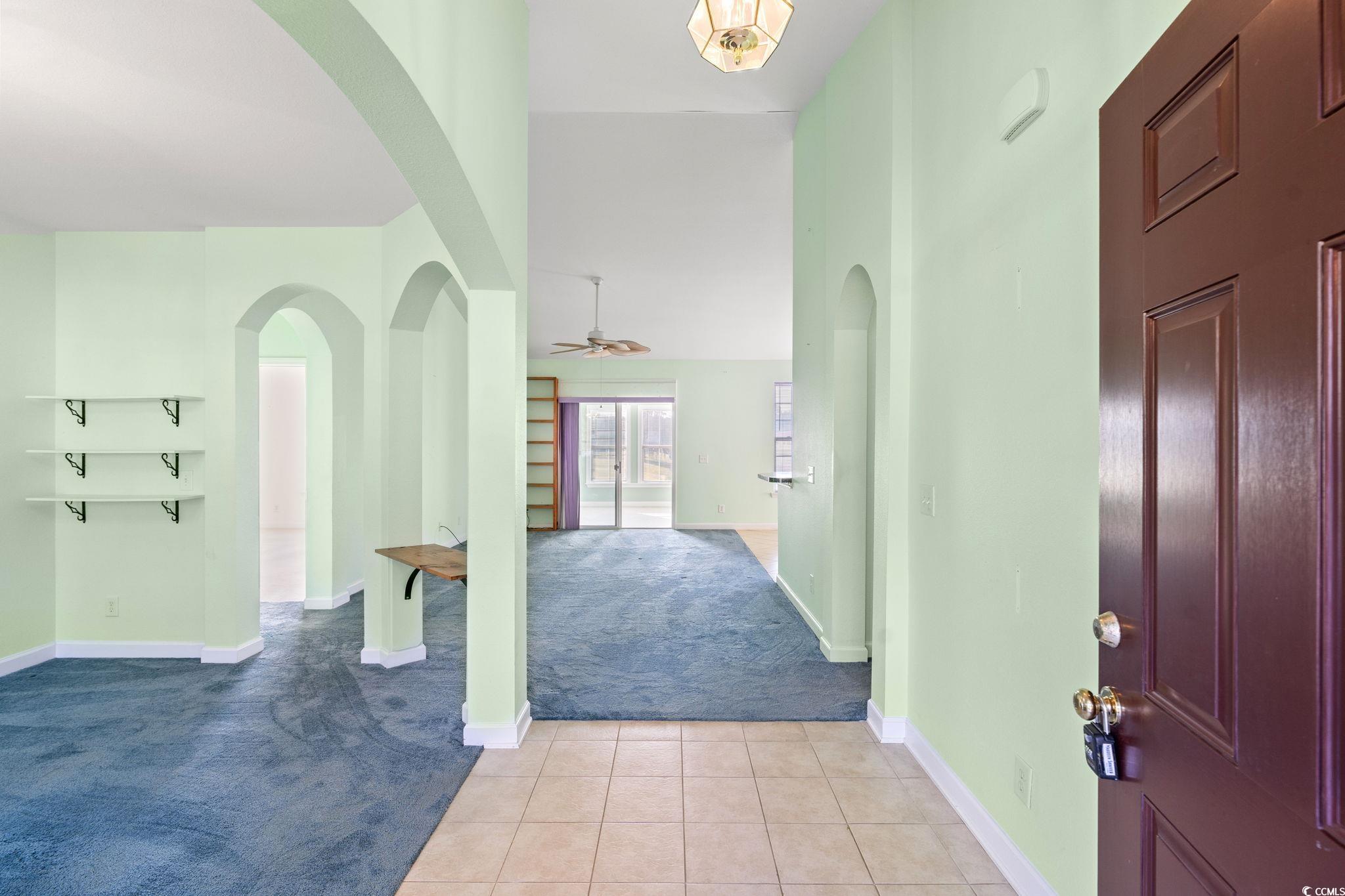875 Brookline Drive Myrtle Beach, SC 29579 - Photo 3 of 40 Carpeted foyer entrance with arched walkways, tile patterned flooring, ceiling fan, and a high ceiling
