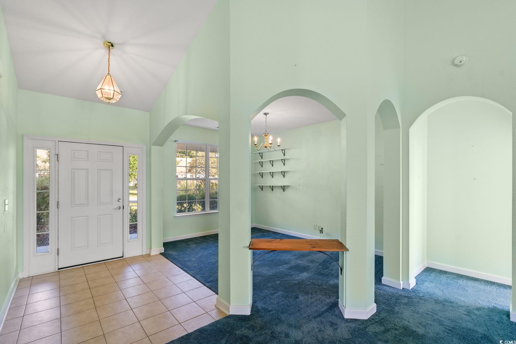 875 Brookline Drive Myrtle Beach, SC 29579 - Photo 5 of 40 Carpeted entrance foyer with tile patterned flooring, a chandelier, a towering ceiling, and arched walkways