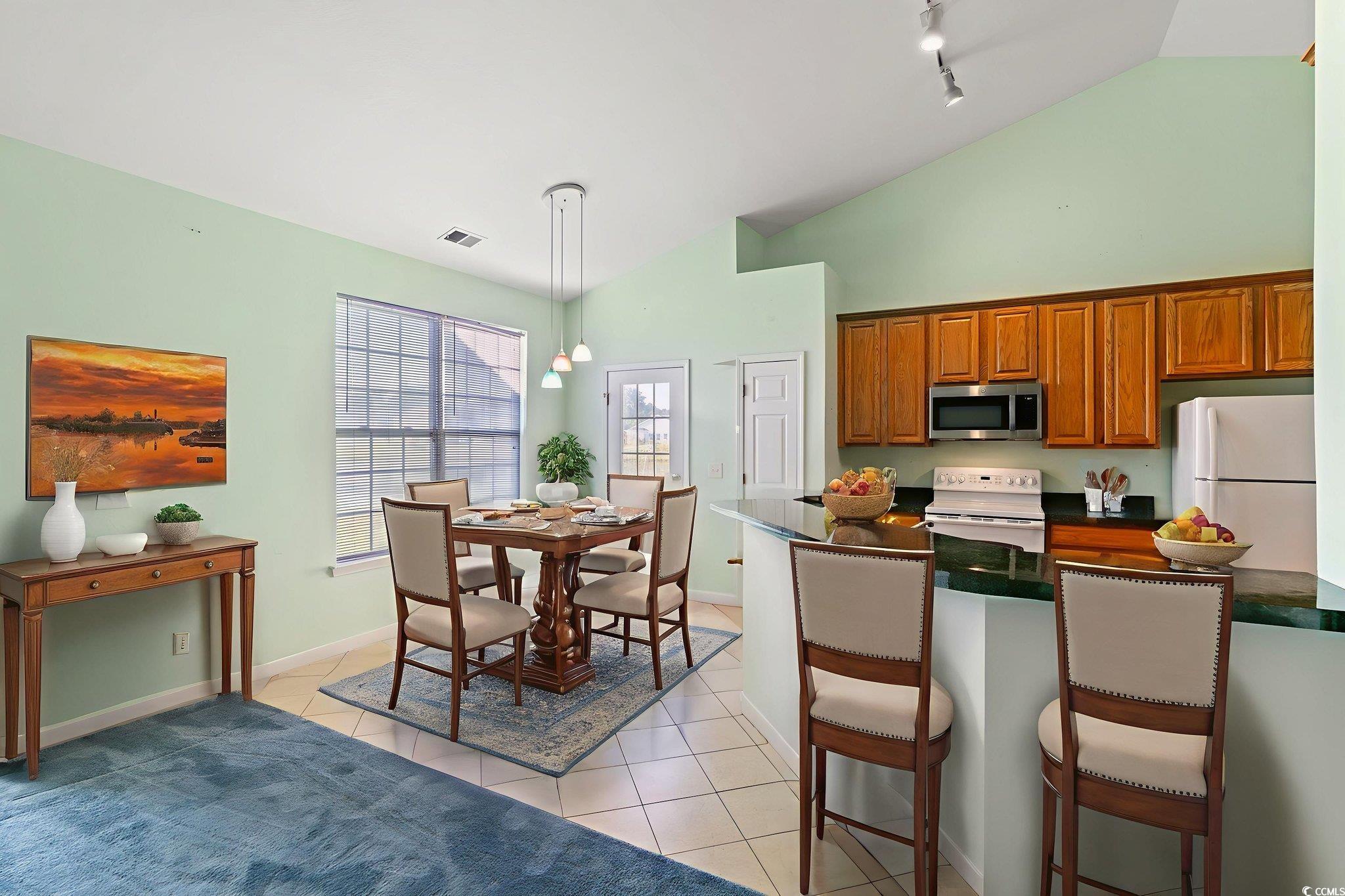 875 Brookline Drive Myrtle Beach, SC 29579 - Photo 10 of 40 Kitchen featuring brown cabinets, white appliances, a kitchen bar, decorative light fixtures, and light tile patterned floors