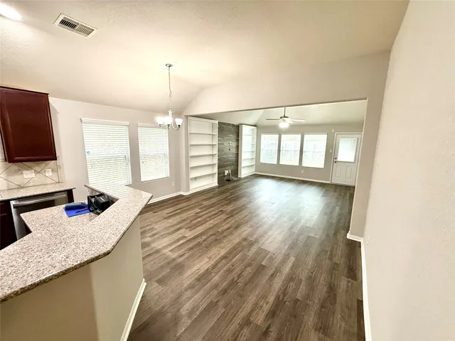 a open kitchen with granite countertop a sink dishwasher a stove and a refrigerator with wooden floor