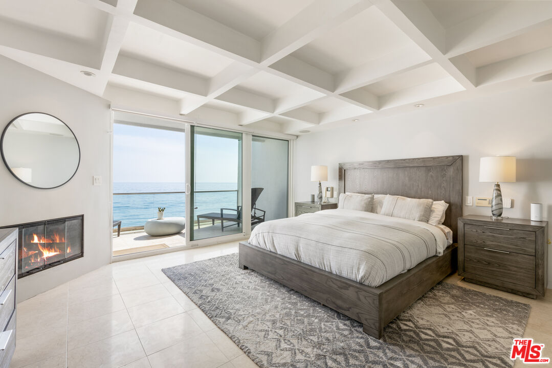 20520 Pacific Coast Highway Malibu, CA 90265 - Photo 16 of 27 a spacious bedroom with a bed a fireplace and a large window