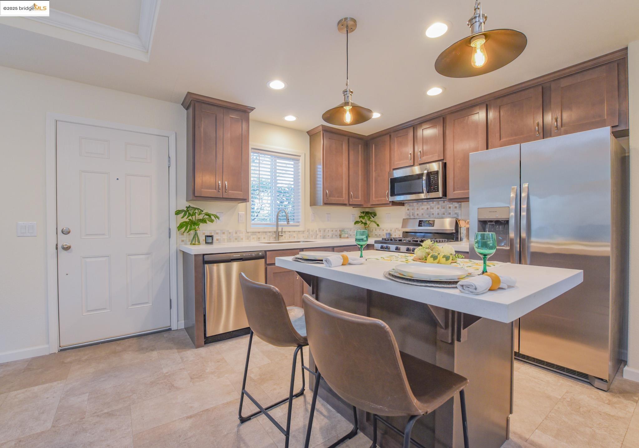 10956 Green Street Columbia, CA 95310 - Photo 9 of 45 Kitchen featuring appliances with stainless steel finishes, a kitchen breakfast bar, a kitchen island, decorative light fixtures, and backsplash