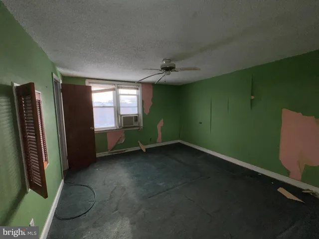an empty room with ceiling fan and window