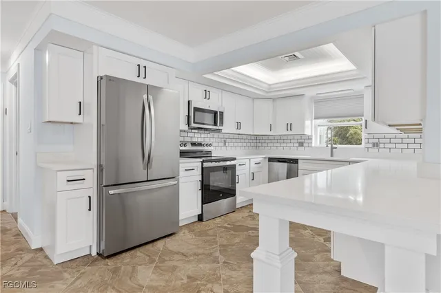 a kitchen with stainless steel appliances kitchen island granite countertop a refrigerator a stove a sink dishwasher and white cabinets with wooden floor