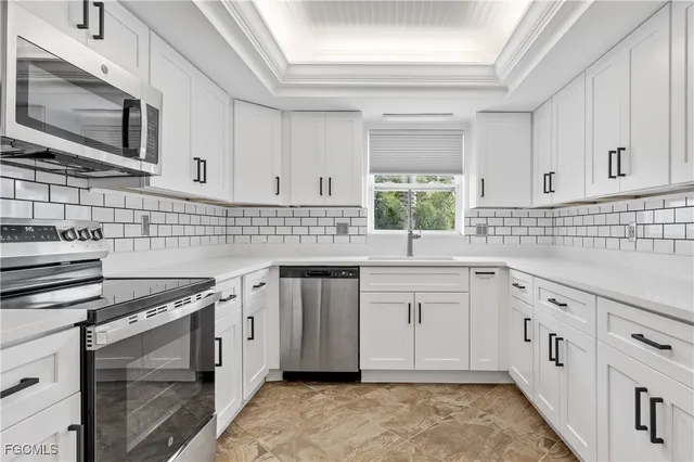 a kitchen with granite countertop white cabinets stainless steel appliances and a sink