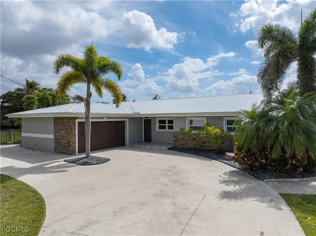 a view of a house with a yard and palm trees