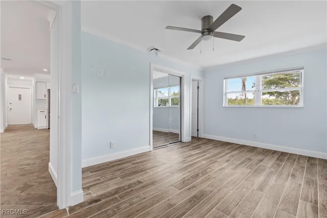 a view of an empty room with a window and wooden floor