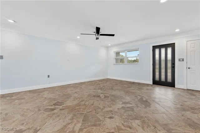 an empty room with ceiling fan and windows