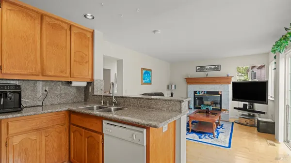 a kitchen with stainless steel appliances granite countertop a stove top oven a sink a dining table and chairs with wooden floor