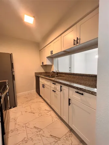 a kitchen with granite countertop a sink a stove and refrigerator