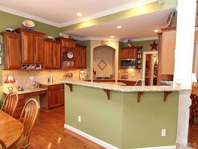 2504 Treen Street Raleigh, NC 27614 - Photo 4 of 13 Deluxe kitchen w/ granite counters, cherry stained cabinets, gas cooktop w/ tile surround, stainless steel appliances, and hardwood floors