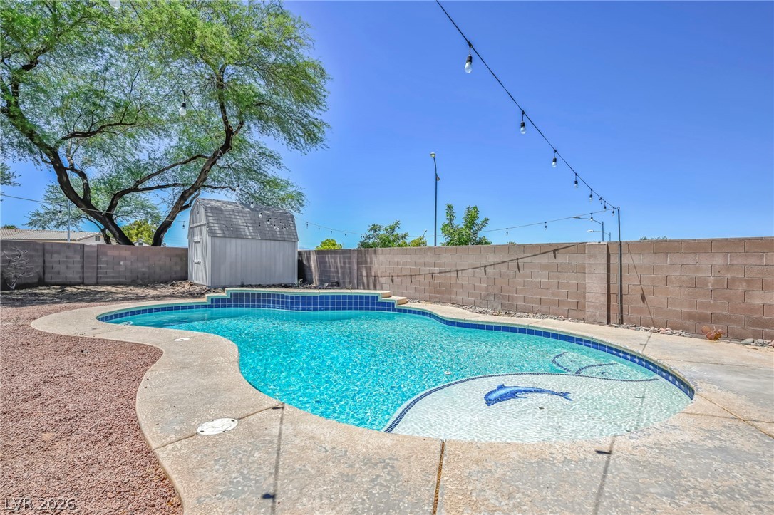 1234 Sunfire Street Henderson, NV 89014 - Photo 35 of 40 A tranquil backyard oasis featuring a freeform swimming pool with a dolphin mosaic and a charming shed.