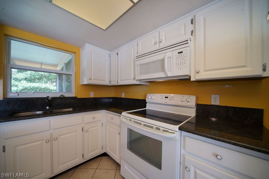 18557 Iris Road Fort Myers, FL 33967 - Photo 4 of 6 a kitchen with granite countertop white cabinets and white appliances