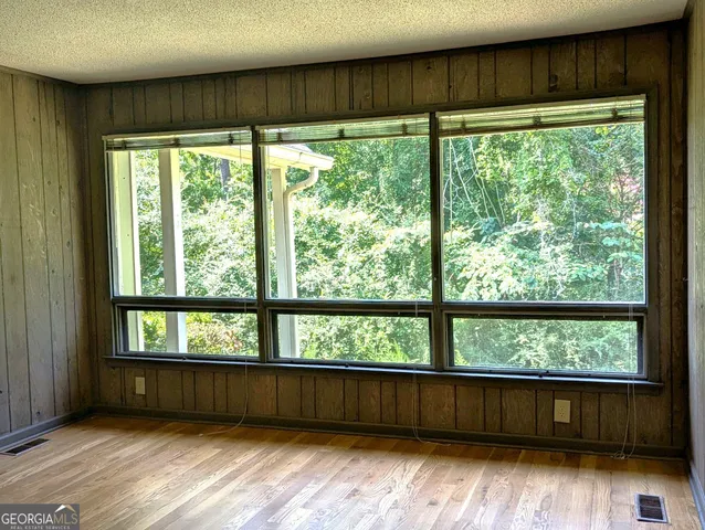 a view of an empty room with wooden floor and a window