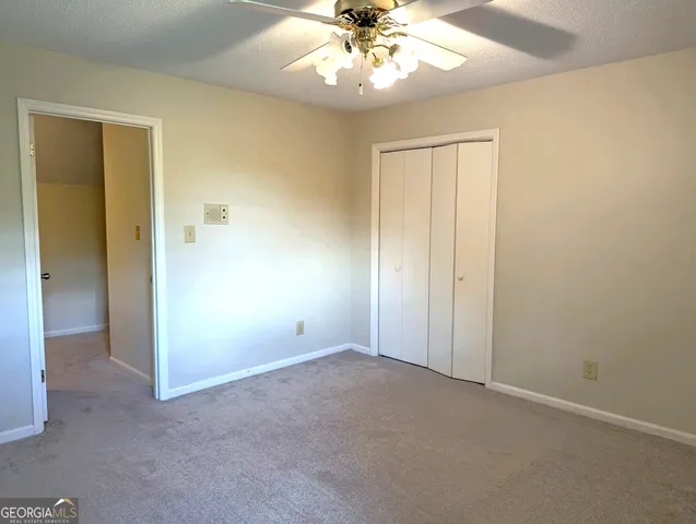 an empty room with a chandelier fan and closet