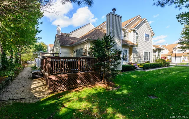 a view of a white house next to a yard with plants and trees