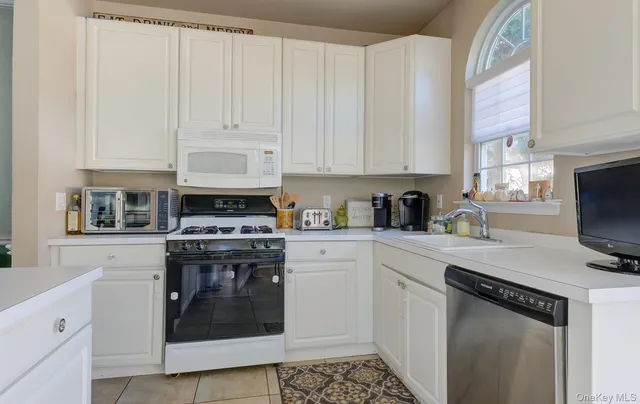 a kitchen with stainless steel appliances granite countertop a stove a sink and a white cabinets