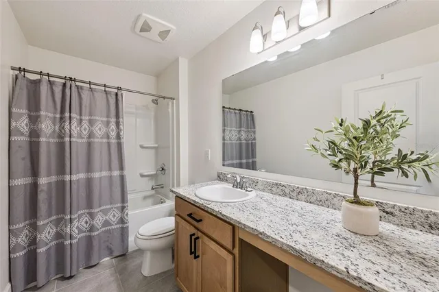 a bathroom with a granite countertop sink a toilet and shower