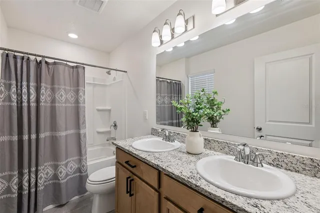 a bathroom with a granite countertop sink a toilet a mirror and shower
