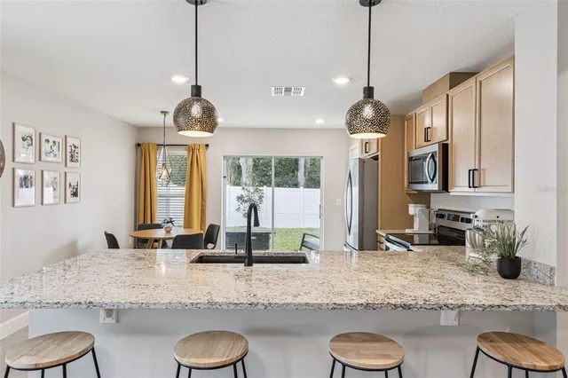 a kitchen with granite countertop a sink a counter top space and living room view