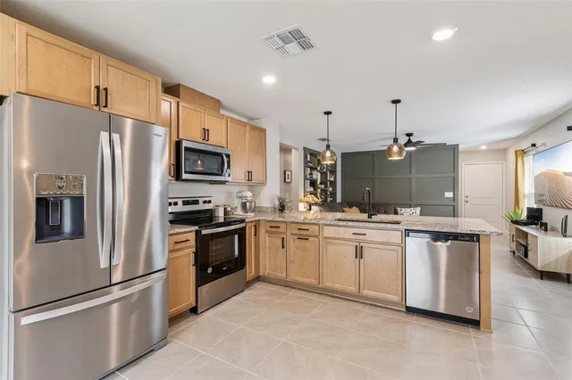 a kitchen with stainless steel appliances granite countertop a refrigerator a stove top oven a sink and dishwasher