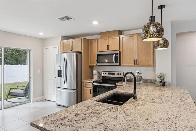 a kitchen with stainless steel appliances granite countertop a sink a stove a refrigerator a washer and dryer