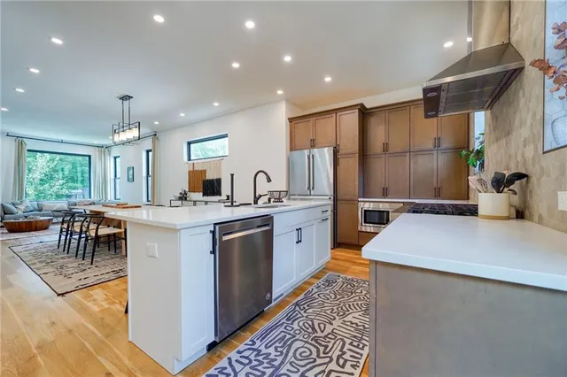 a kitchen with stainless steel appliances granite countertop a refrigerator a sink dishwasher a oven with white cabinets and wooden floor