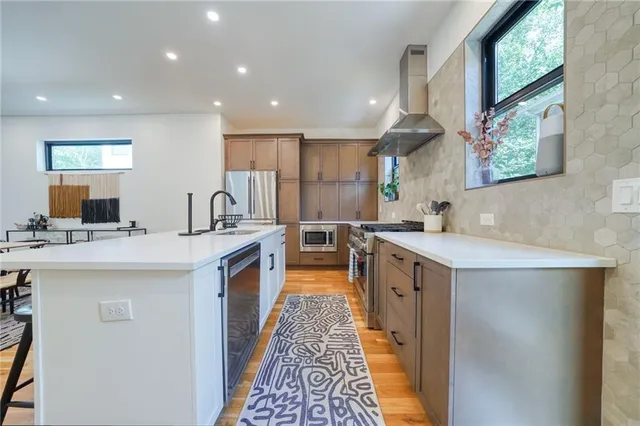 a large kitchen with stainless steel appliances a sink and a large window