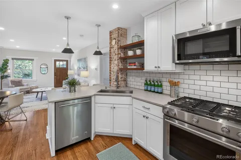 a kitchen with stainless steel appliances a sink dishwasher a stove and white cabinets with wooden floor