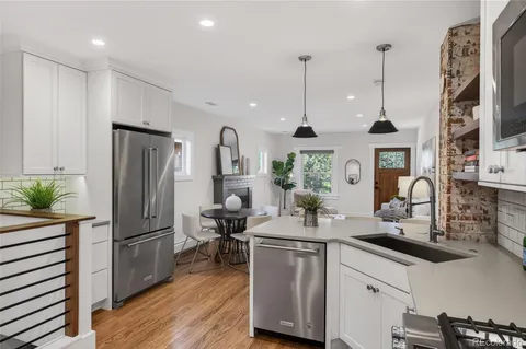 a kitchen with stainless steel appliances granite countertop a refrigerator a sink dishwasher and a wooden floor
