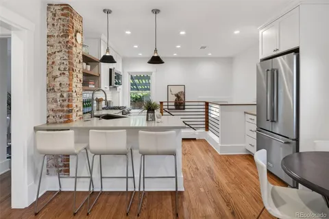 a kitchen with stainless steel appliances kitchen island granite countertop a table chairs and a refrigerator