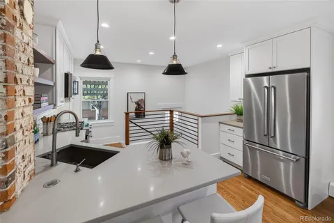 a kitchen with stainless steel appliances a sink a counter space a refrigerator and chairs