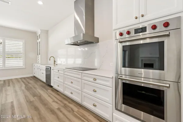 a large kitchen with kitchen island a stove a sink a center island and wooden floor