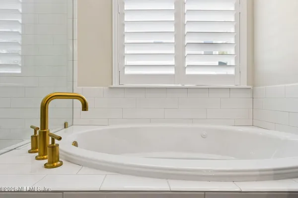 a bathroom with a granite countertop sink a mirror a bathtub and shower